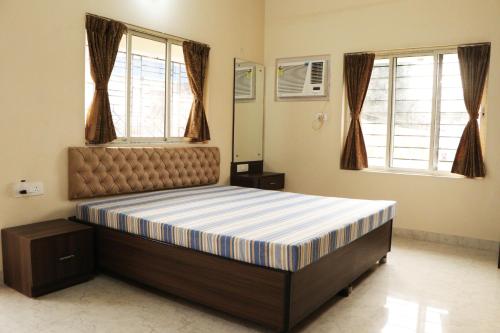 a bedroom with a bed in a room with windows at Radharani Apartment in Kolkata