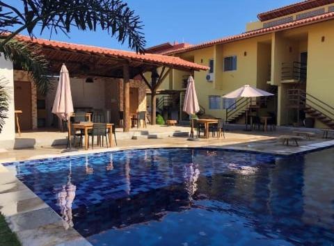 a swimming pool in front of a house with umbrellas at Apartamento Sossego in Luis Correia