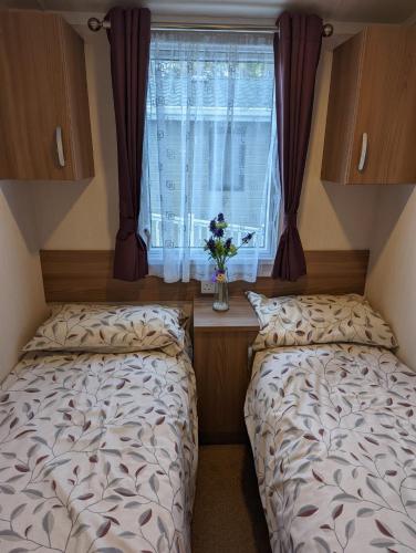 two beds in a small room with a window at Caravan Littlesea Haven Weymouth Amazing Views in Weymouth