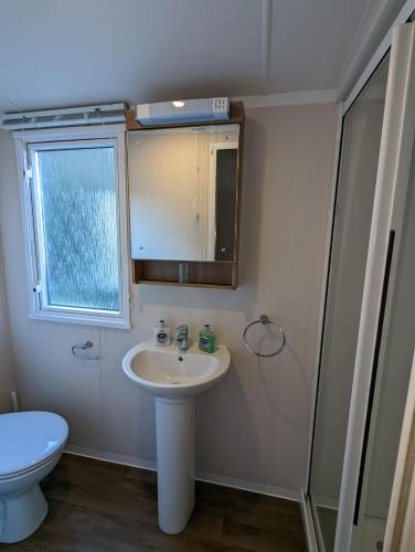 a bathroom with a sink and a toilet and a mirror at Caravan Littlesea Haven Weymouth Amazing Views in Weymouth