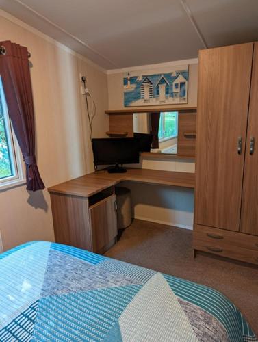a bedroom with a desk and a computer in it at Caravan Littlesea Haven Weymouth Amazing Views in Weymouth