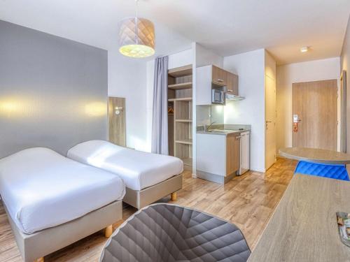una camera d'albergo con due letti e una cucina di Aparthotel Adagio Access Saint Nazaire a Saint-Nazaire