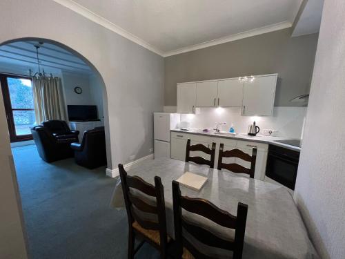 a kitchen and living room with a table and chairs at Eden Vale Garden View Apartment with Patio in Morecambe