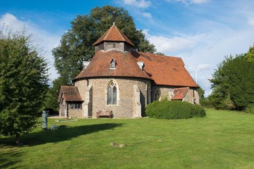 an old church with a red roof on a green field at The Stables, relax in 5 star style and comfort with lovely walks all around in Great Maplestead