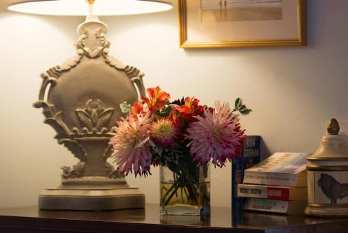 a vase of flowers on a table next to a lamp at The Stables, relax in 5 star style and comfort with lovely walks all around in Great Maplestead