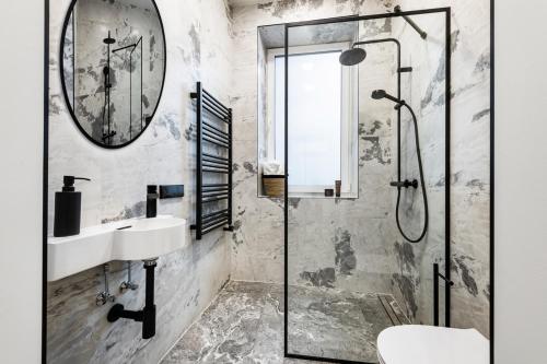 uma casa de banho com um chuveiro, um lavatório e um espelho. em Oldtown Trinity House em Kaunas
