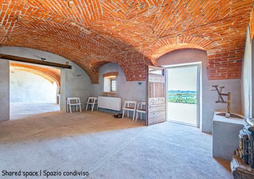 Casa di nonna Ines 1 - Hideaway in Monferrato con Vista sulle Colline, Solarium e Piscina في Gabiano: غرفة بجدار من الطوب وسقف من الطوب