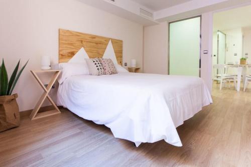 1 dormitorio con 1 cama blanca grande y cabecero de madera en Apartments Olé - Albareda 24, en Sevilla