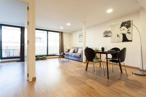 Apartments Olé - Albareda 24 في إشبيلية: غرفة معيشة مع طاولة وكراسي وأريكة