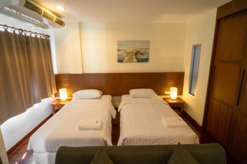 a hotel room with three beds and a window at Baan Chuan Chom Pattaya in Pattaya Central