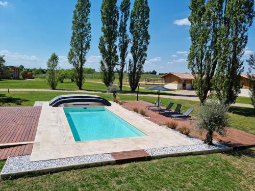 - une piscine dans une cour avec 2 chaises dans l'établissement Logement de charme en campagne girondine: le Domaine de Mongeret, à Pondaurat