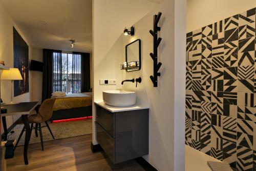 łazienka z umywalką oraz sypialnia z łóżkiem w obiekcie Stadsslaperij B&B w mieście Tilburg