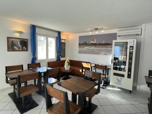 - une salle à manger avec des tables et des chaises en bois dans l'établissement Hôtel Les Arcades, à Saintes-Maries-de-la-Mer