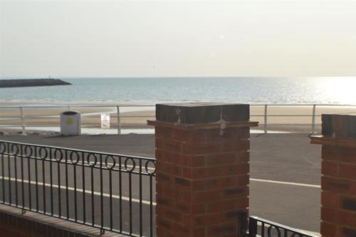 a view of a beach with a fence and the ocean at Beachfront pet friendly townhouse, Stunning views in Port Talbot