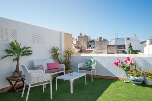 a rooftop patio with chairs and tables and plants at Albareda Olehousing in Seville