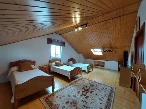 NedaにあるAcogedora casa de campo-PISO Y ATICO con finca-のベッド2台とテレビが備わる屋根裏部屋です。