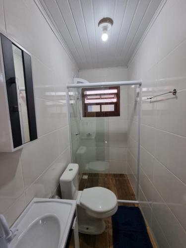 a white bathroom with a toilet and a sink at Pousada do Primo in Capão da Canoa