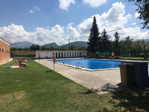 una piscina con gente tirada en el césped junto a un edificio en Cal Cuaresma en Isona