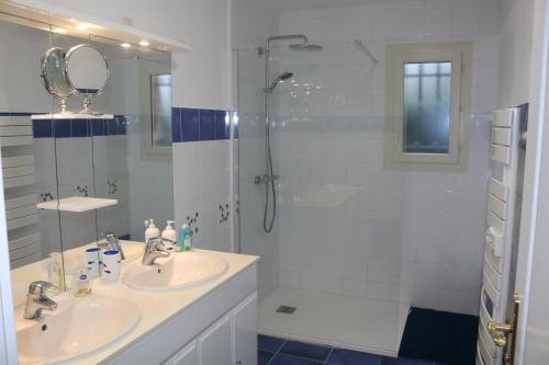 a white bathroom with two sinks and a shower at Le Camp De Ferie in Monpazier