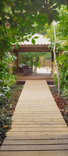 a wooden walkway in a garden with a pavilion at Pousada Vila Araticum in Santo André
