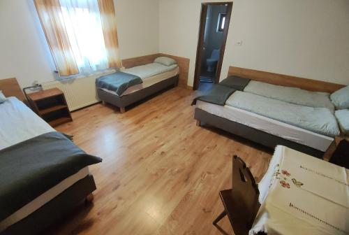 a room with two beds in a room with wooden floors at Zajazd PTTK Pod Roztoką in Rytro