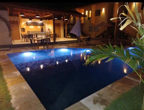 una piscina iluminada por la noche con luces en Condomínio Villamares en Luis Correia