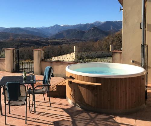 una bañera de hidromasaje en un patio con mesa y sillas en Lo Boix Le Mas, en Saint-Laurent-de-Cerdans