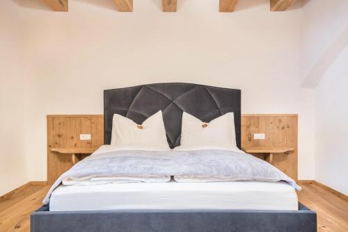 1 dormitorio con 1 cama grande y cabecero negro en Alpin Chalet Samer Apt Berghütte, en Sarentino