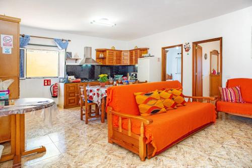 sala de estar con sofá naranja y cocina en Casa Juana, en Agua de Fontanales