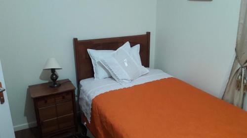 1 cama con manta naranja y almohadas blancas en LOMAS DE CASTRO, en Castro