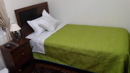 1 dormitorio con cama verde y mesita de noche en LOMAS DE CASTRO, en Castro