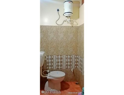 een badkamer met een toilet en een lampje aan de muur bij Hotel Shanti Heritage, Guna in Guna