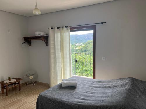 um quarto com uma cama e uma grande janela em Casa Nascimento Vista Panorâmica Serra São José em Tiradentes