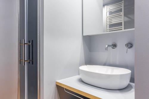 La salle de bains est pourvue d'un lavabo blanc sur un comptoir. dans l'établissement Easylife - Accogliente e moderno bilocale in zona Navigli, à Milan