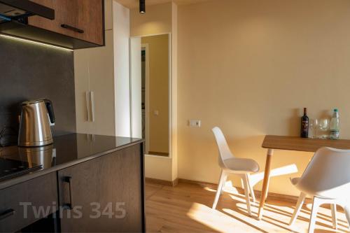 a kitchen with a table and white chairs in a room at Valley & Mountain View, Twins, with Hot Water in Gudauri