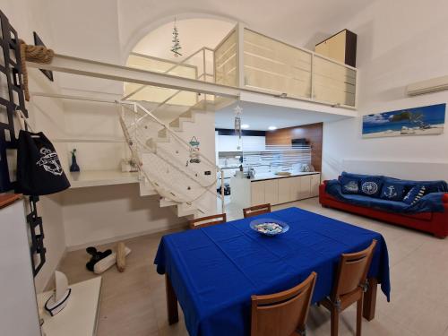 a dining room with a blue table and a kitchen at Polignano a Mare: sulla piazza di Domenico Modugno in Polignano a Mare