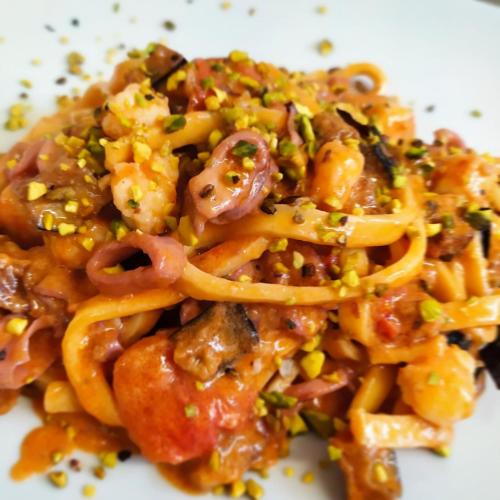 a white plate of pasta with onions and peppers at Hotel Al Rustico in Crosia