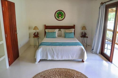 a bedroom with a large bed with blue pillows at Suites Taipe in Trancoso