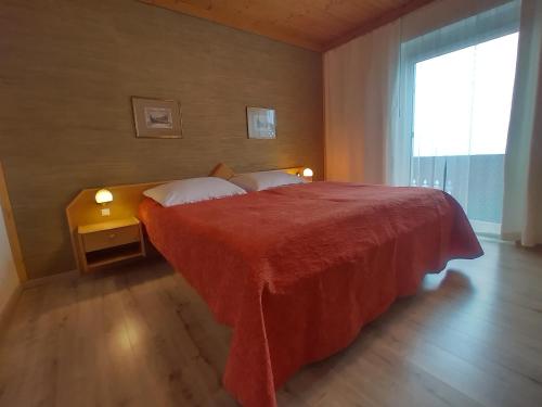 a bedroom with a large red bed with a window at Seeblick-Appartements Ossiach in Ossiach