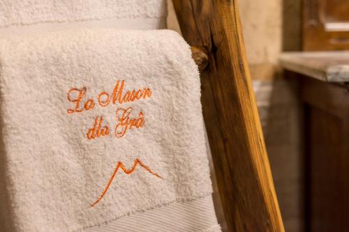 a towel with a red writing on the side of a bed at La Mason dla Grà in Frassinetto