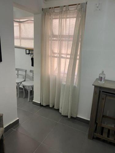 sala de estar con ventana, mesa y silla en Departamento Calle Vicente Zapata en Mendoza