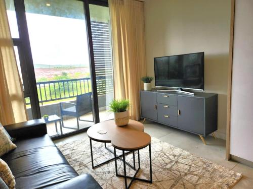a living room with a couch and a tv and a table at Zimbali Lakes Boulevard Suites, Unit148 in Ballito