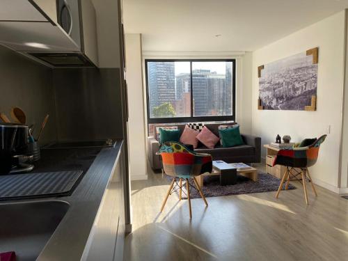 a living room with a couch and a kitchen with a window at Apartamento Park Way Bogotá in Bogotá