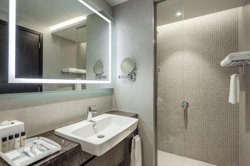 a bathroom with a sink and a shower with a mirror at Somerset Downtown Al Khobar in Al Khobar