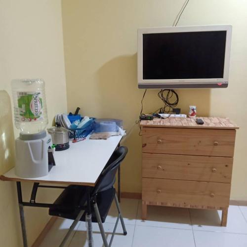 scrivania con TV sopra un comò in legno di Home Stay JM a Shah Alam