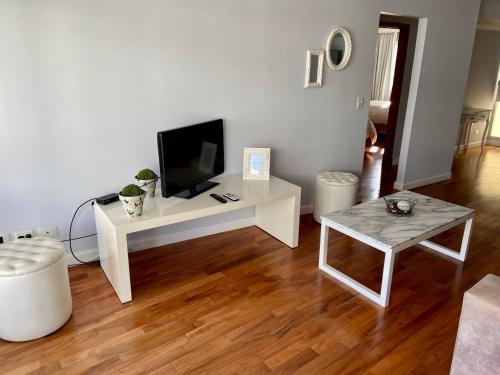 a living room with a white table and a tv at Departamentos de Categoría, Santa Fé y Alberti in Mar del Plata