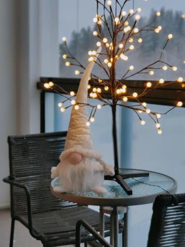 a gnome sitting on a table next to a tree with lights at Joutjärven Studio Apartment in Lahti
