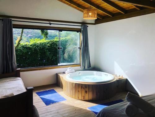 bañera en una habitación con ventana grande en Pousada Watu Kerere, en Praia do Rosa