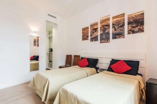 Cette chambre comprend 2 lits avec des murs blancs et des oreillers rouges. dans l'établissement Piazza San Pietro Suite, à Rome