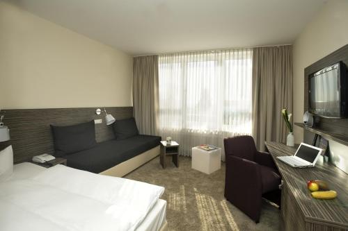 a hotel room with a bed and a couch at Best Western Plus Atrium Hotel in Ulm
